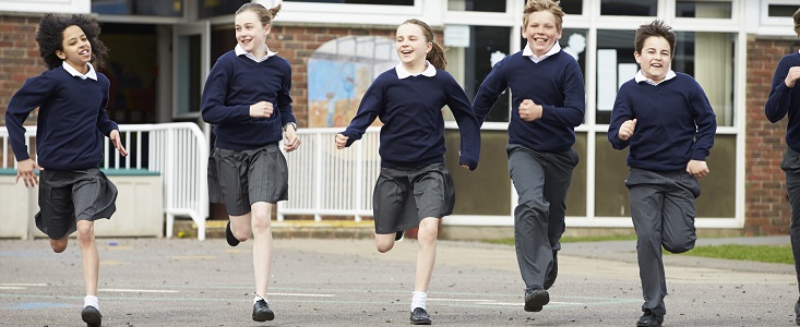 Group Of Elementary School Pupils Running In Playground